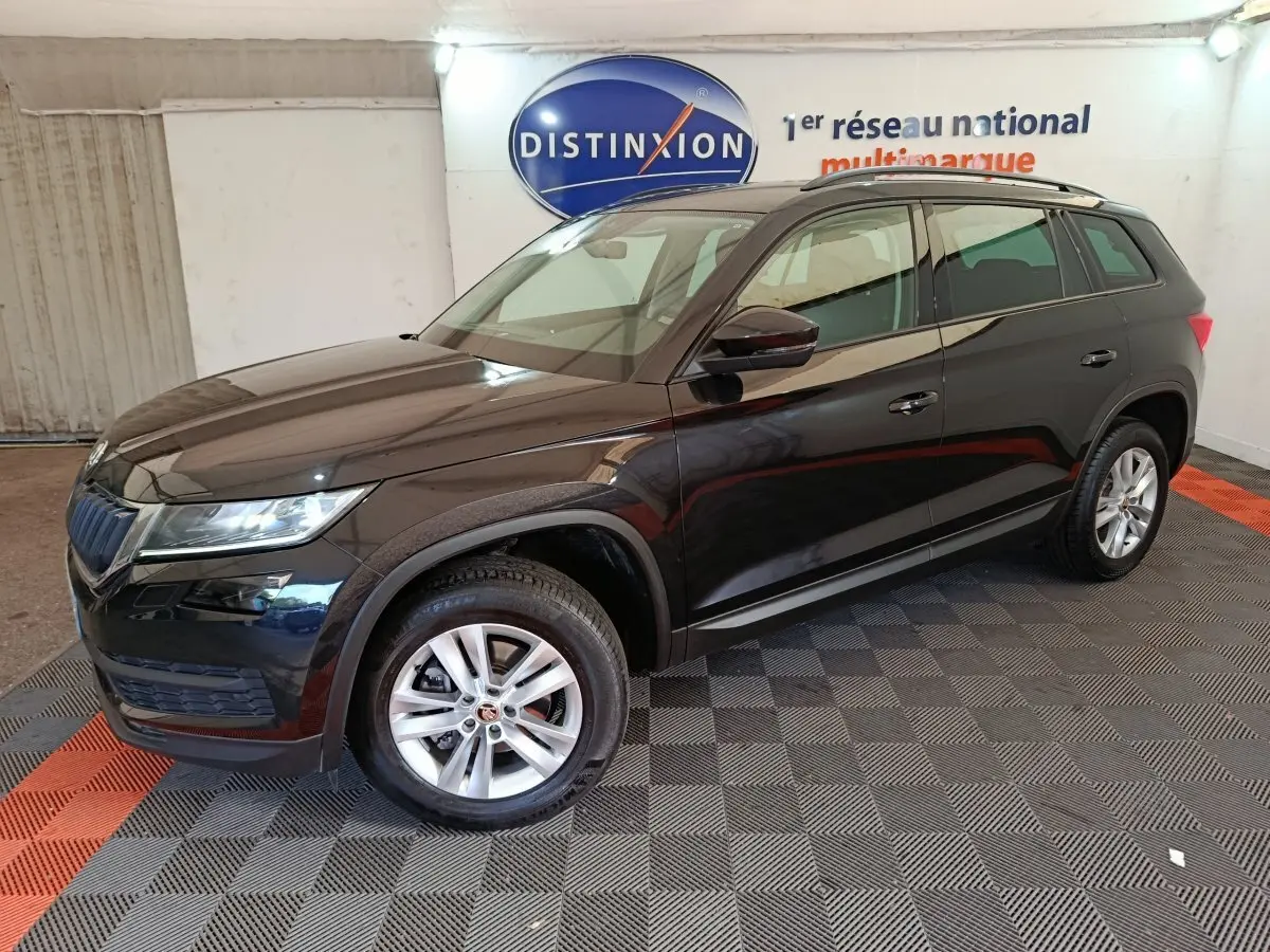 Vue 3/4 avant droite d'un SUV SKODA KODIAQ noir 2021 finition Ambition, roues alliage et barres de toit noires visibles.