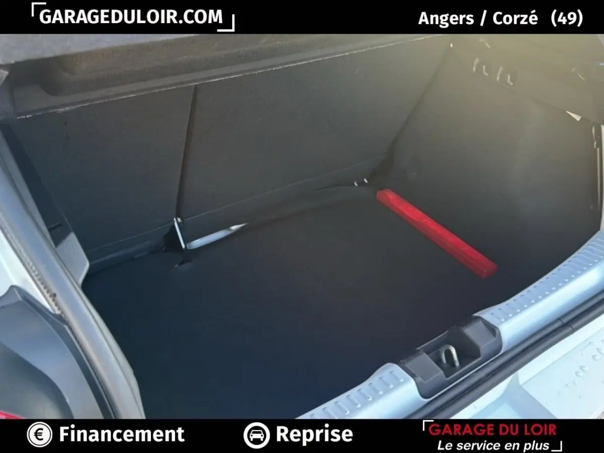 Coffre ouvert d’une Dacia Sandero blanche 2025, vue arrière montrant un espace de chargement propre avec triangle de signalisation rouge.