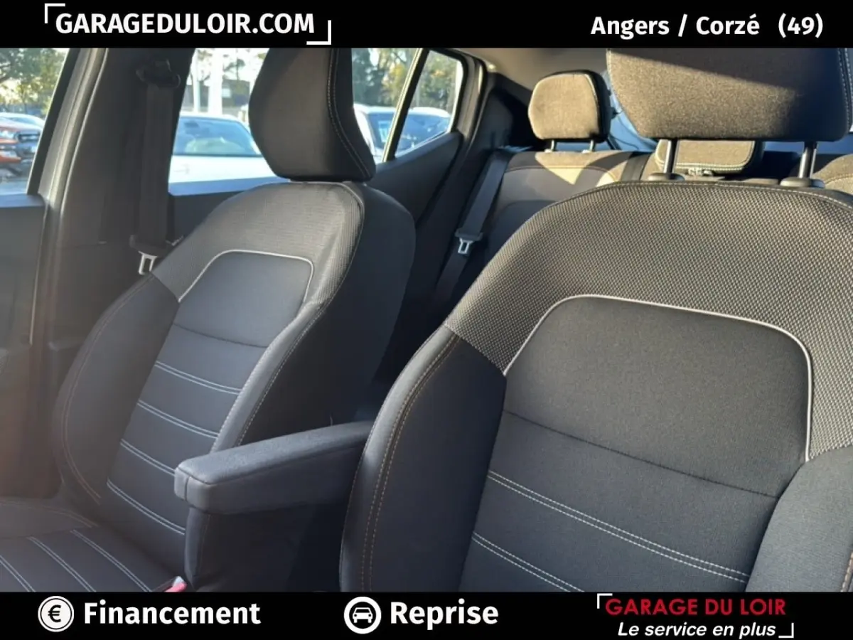 Vue intérieure sur les sièges avant en tissu gris avec surpiqûres blanches de la Dacia Sandero Expression TCe 90 2025.