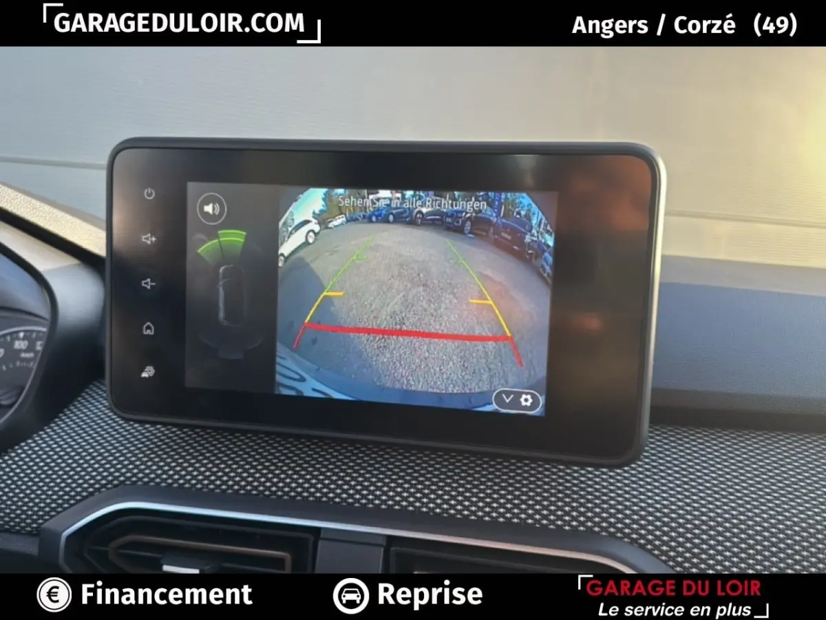 Écran central de la Dacia Sandero Expression TCe 90 2025 montrant la caméra de recul avec lignes de guidage colorées.