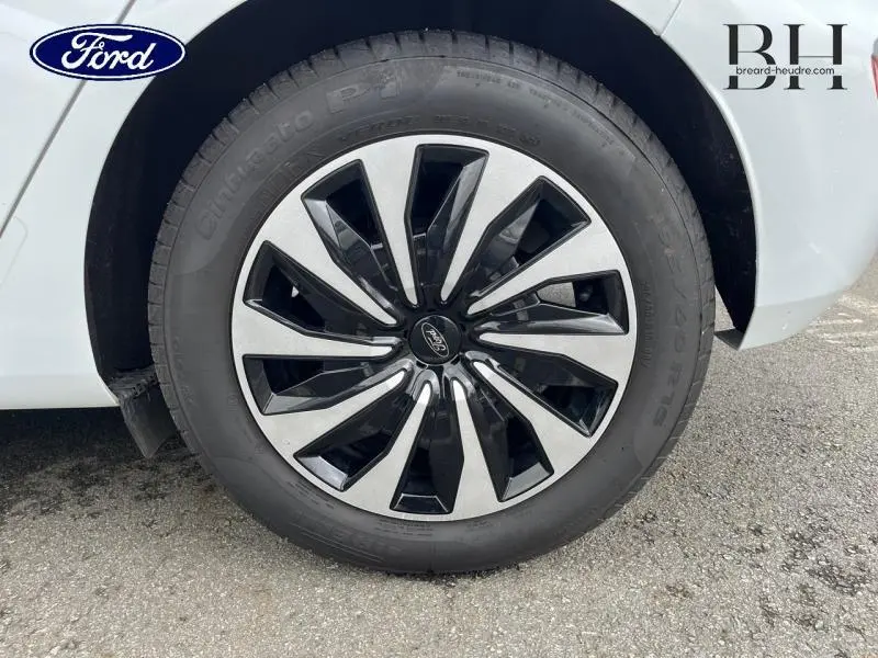 Gros plan sur la roue avant droite d'une Ford Fiesta blanc glacier avec jante alu bicolore au design moderne.