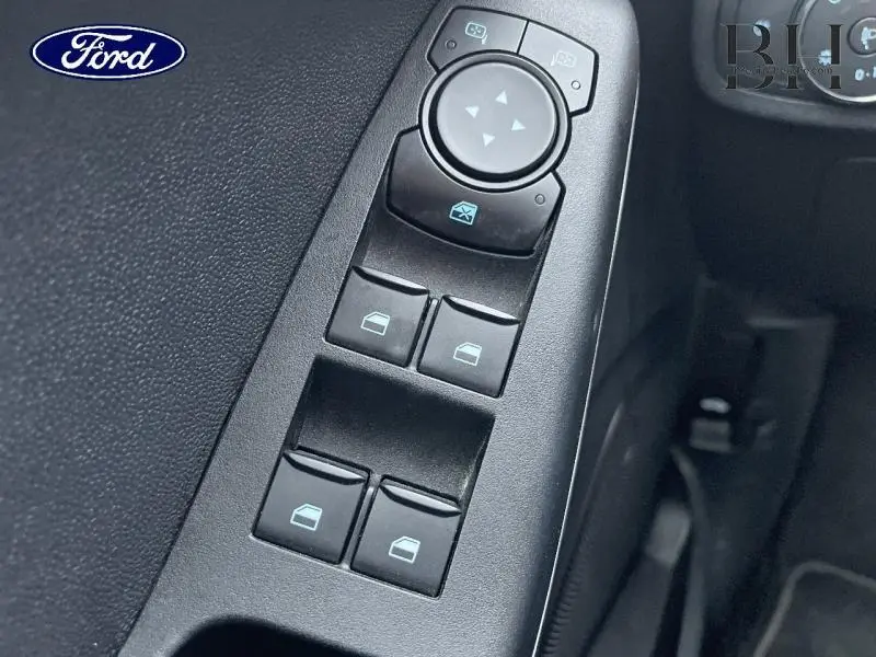 Gros plan sur les commandes des vitres électriques et rétroviseurs côté conducteur d'une Ford Fiesta Blanc Glacier 2022.