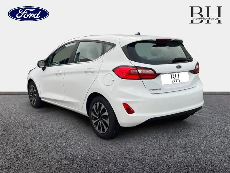 Ford Fiesta blanc glacier vue 3/4 arrière droit, avec jantes alu et becquet arrière distinctifs.