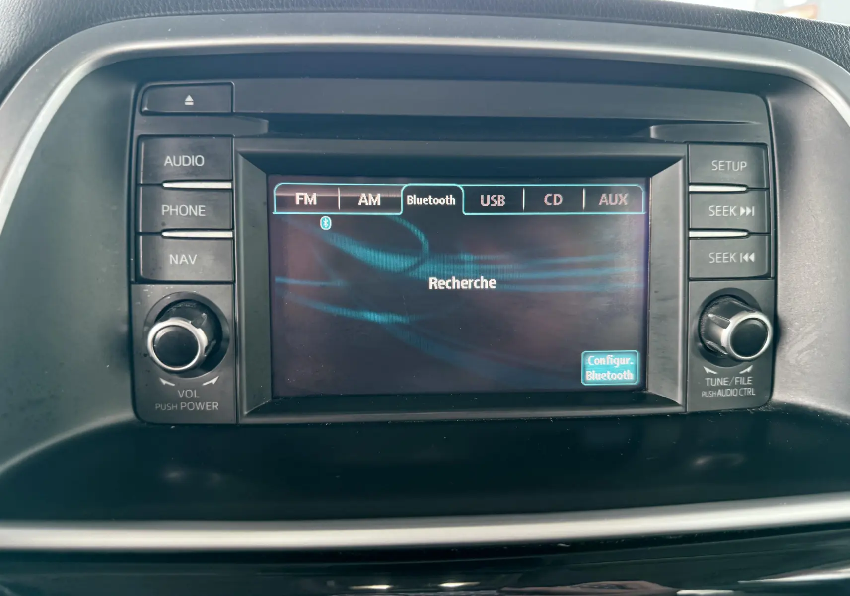 Écran central de la Mazda CX-5 2013 montrant la recherche Bluetooth avec commandes audio autour de l'écran.