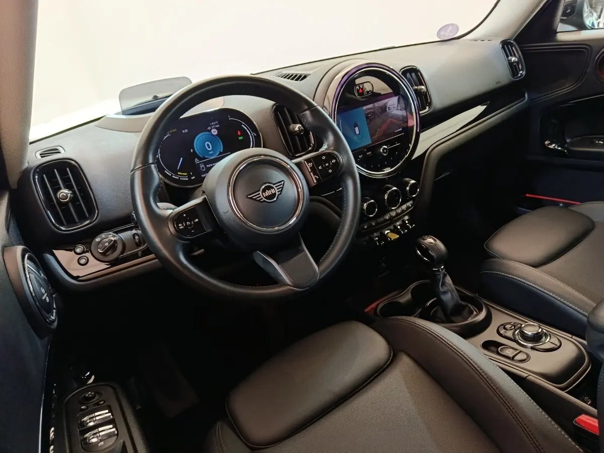 Vue intérieure côté conducteur du MINI Countryman Cooper SE noir, avec tableau de bord digital et écran central tactile rond.