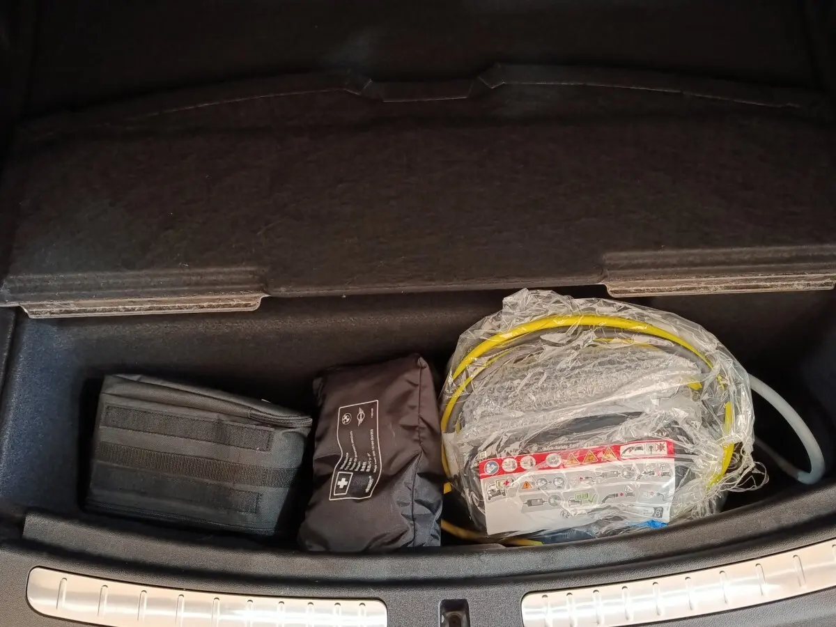 Vue plongeante sur le rangement réfrigéré noir du coffre du MINI Countryman Cooper SE 2023 avec câble de charge emballé.