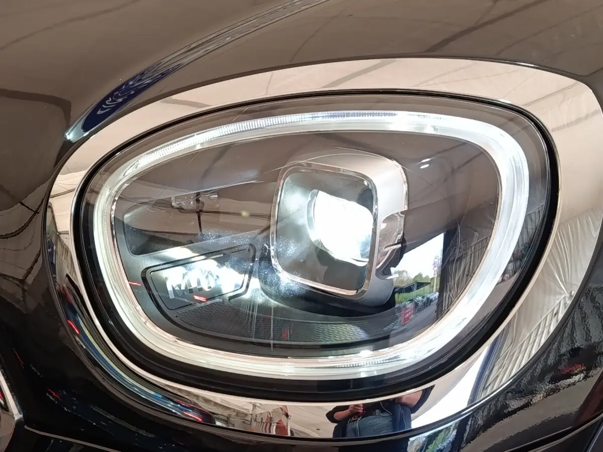 Gros plan sur le phare avant droit LED d’un MINI Countryman Cooper SE noir, soulignant le contour chromé et la signature lumineuse distinctive.
