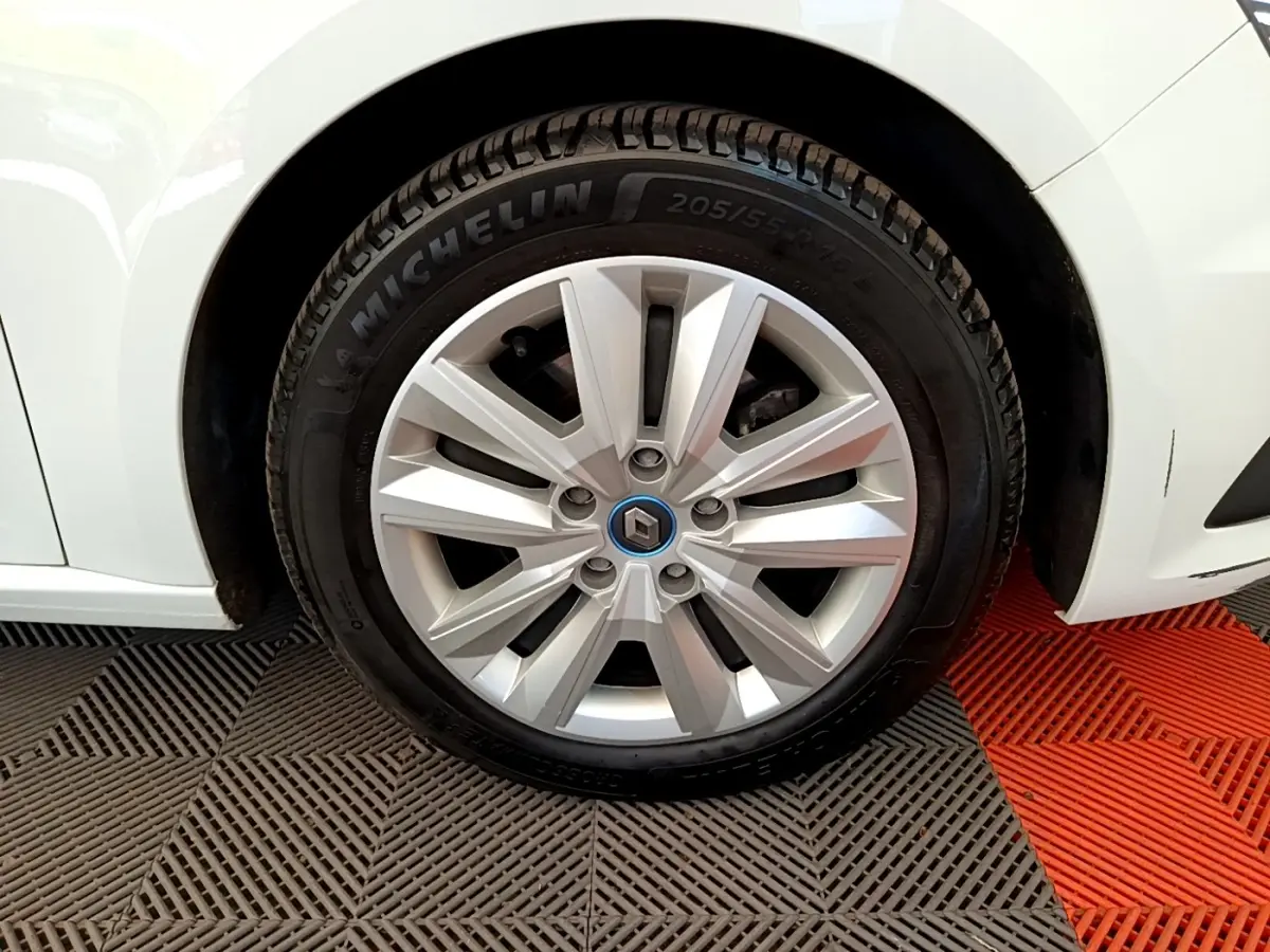 Gros plan sur la roue avant droite d’une Renault Mégane Business E-Tech hybride blanche avec jante argentée et logo Renault bleu.