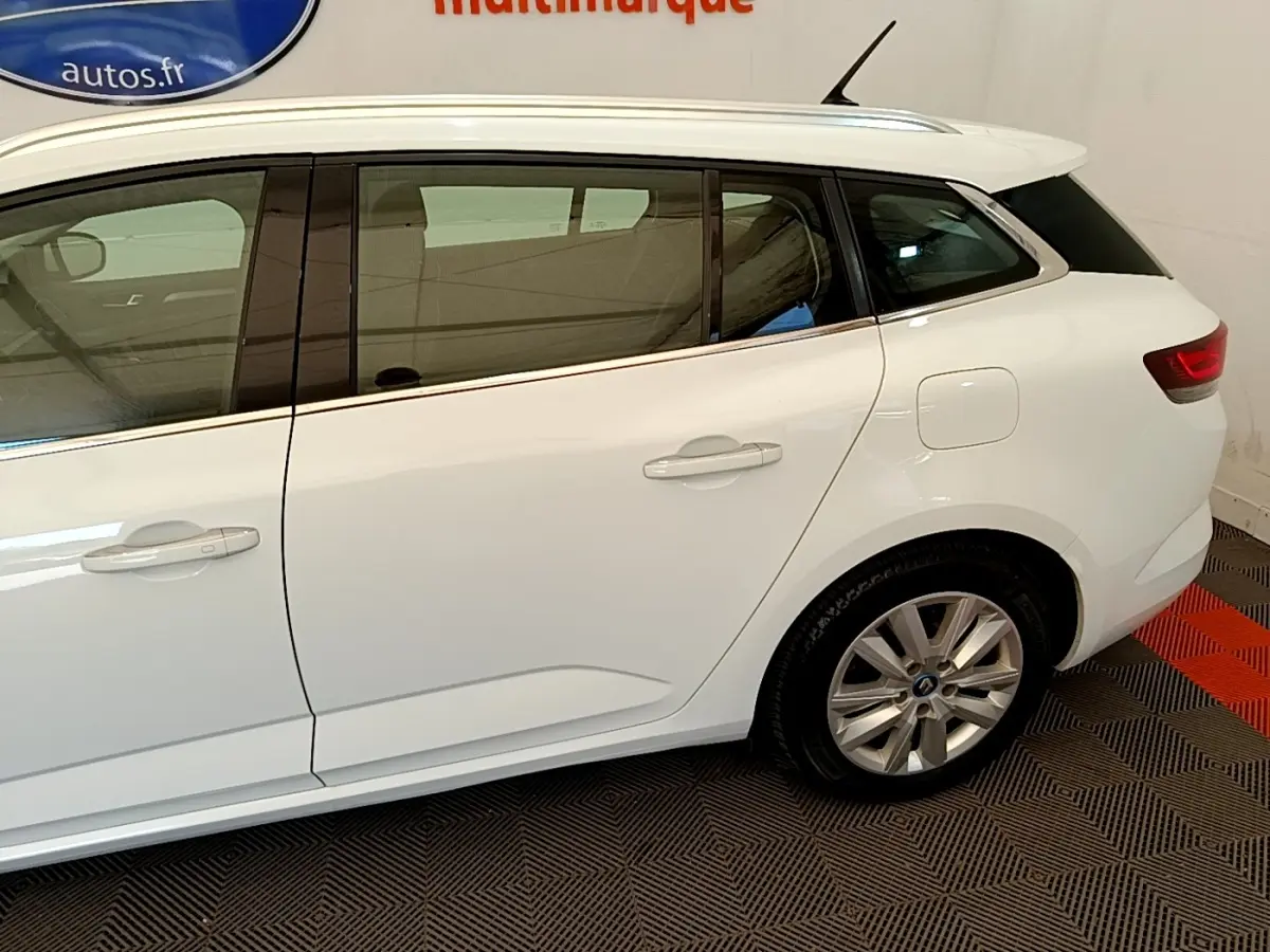 Profil droit d'une Renault Mégane Business E-Tech hybride rechargeable blanche, avec jantes alliage et vitres teintées.