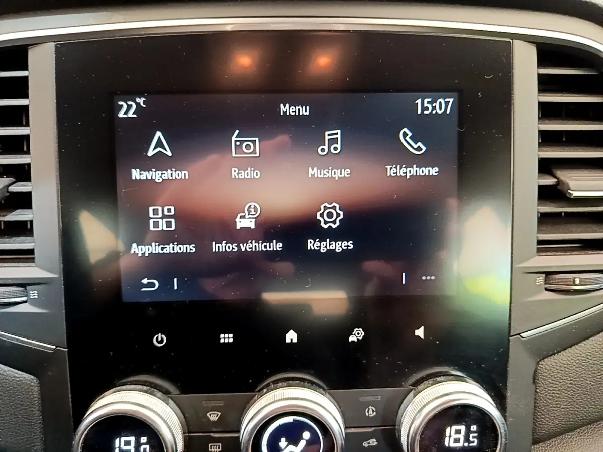 Écran tactile central du tableau de bord de la Renault Mégane Business E-Tech hybride, avec commandes climatisation visibles.