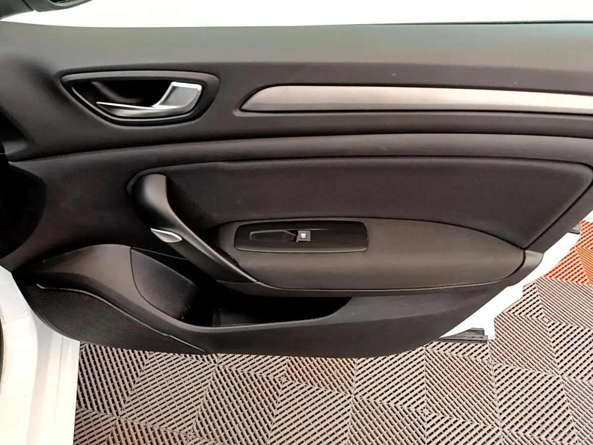 Vue rapprochée de la porte intérieure côté conducteur d’une Renault Mégane Business E-Tech blanche, avec poignée noire et bouton de vitre.