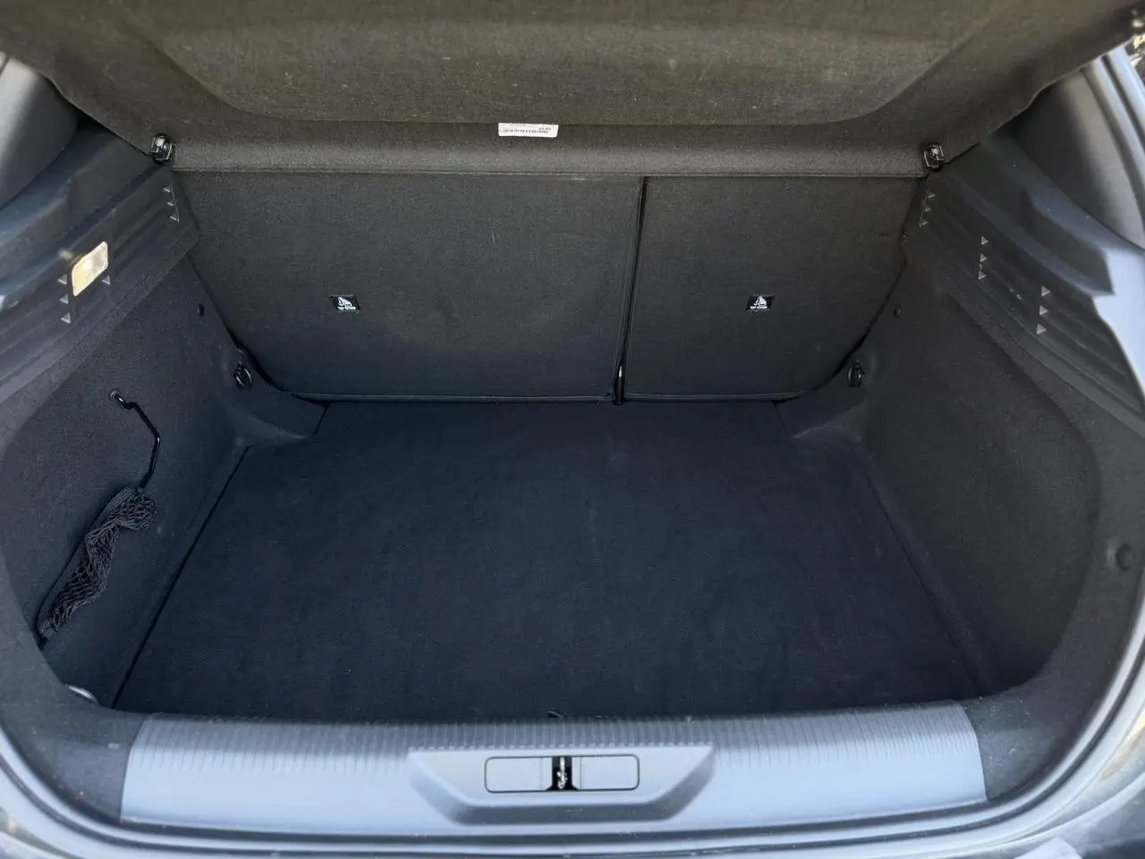 Coffre ouvert vu de face, intérieur noir avec revêtement tissu et filet de rangement latéral visible.