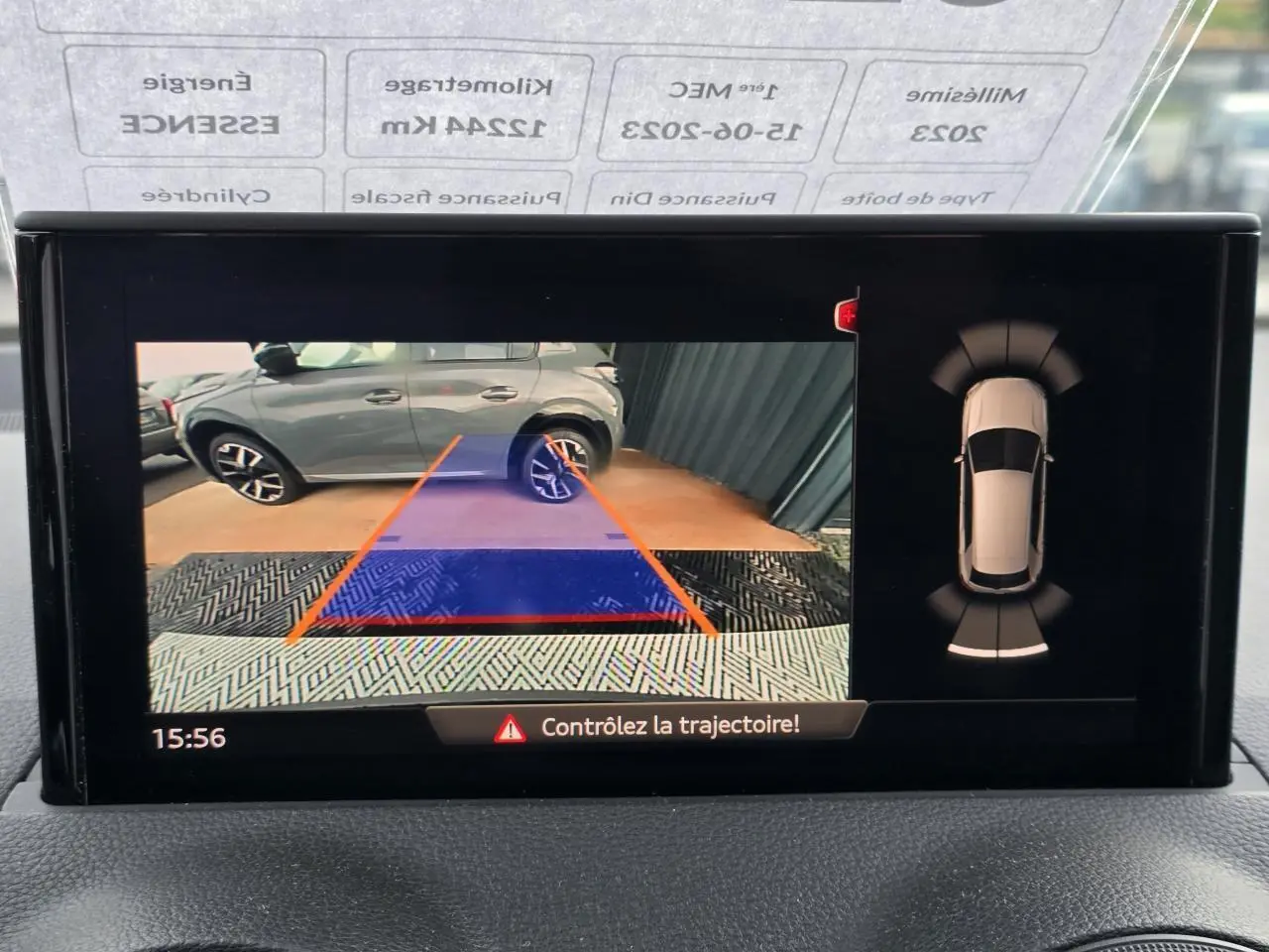 Vue caméra de recul montrant un SUV gris garé à côté, avec lignes de guidage orange et bleu à l'écran.