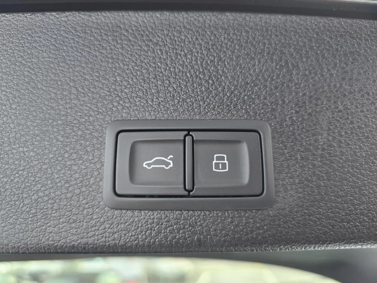 Boutons d'ouverture du coffre et de verrouillage intégrés dans le revêtement intérieur noir du hayon d'un Audi Q2 noir Mythic 2023.
