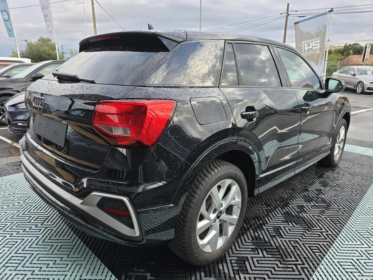 Audi Q2 noir mythic vue 3/4 arrière droit avec vitres surteintées et jantes aluminium 5 branches doubles.