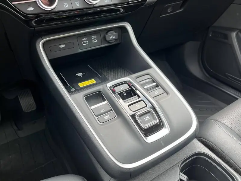 Gros plan sur la console centrale noire du Honda CR-V 2024 hybride avec commandes de boîte automatique et prises USB.