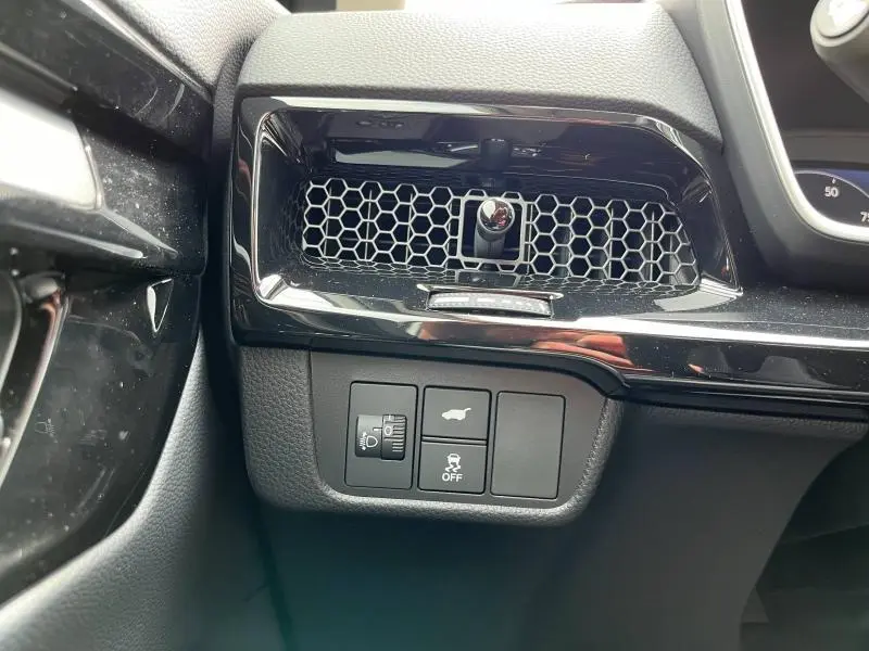 Détail de la console côté conducteur du Honda CR-V 2024 blanc platine, avec commandes d'éclairage et ouverture de coffre.