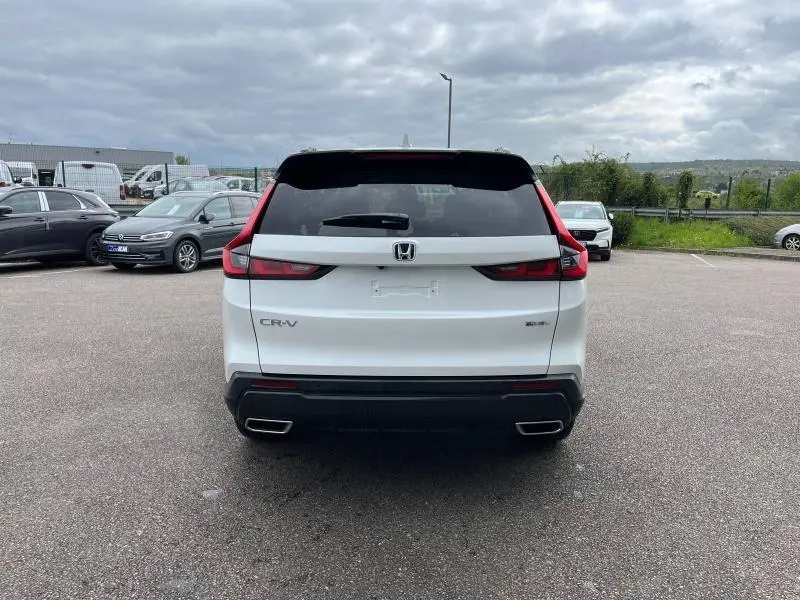 Vue arrière d'un Honda CR-V blanc platine nacrée 2024 avec feux arrière LED et double sortie d'échappement chromée.