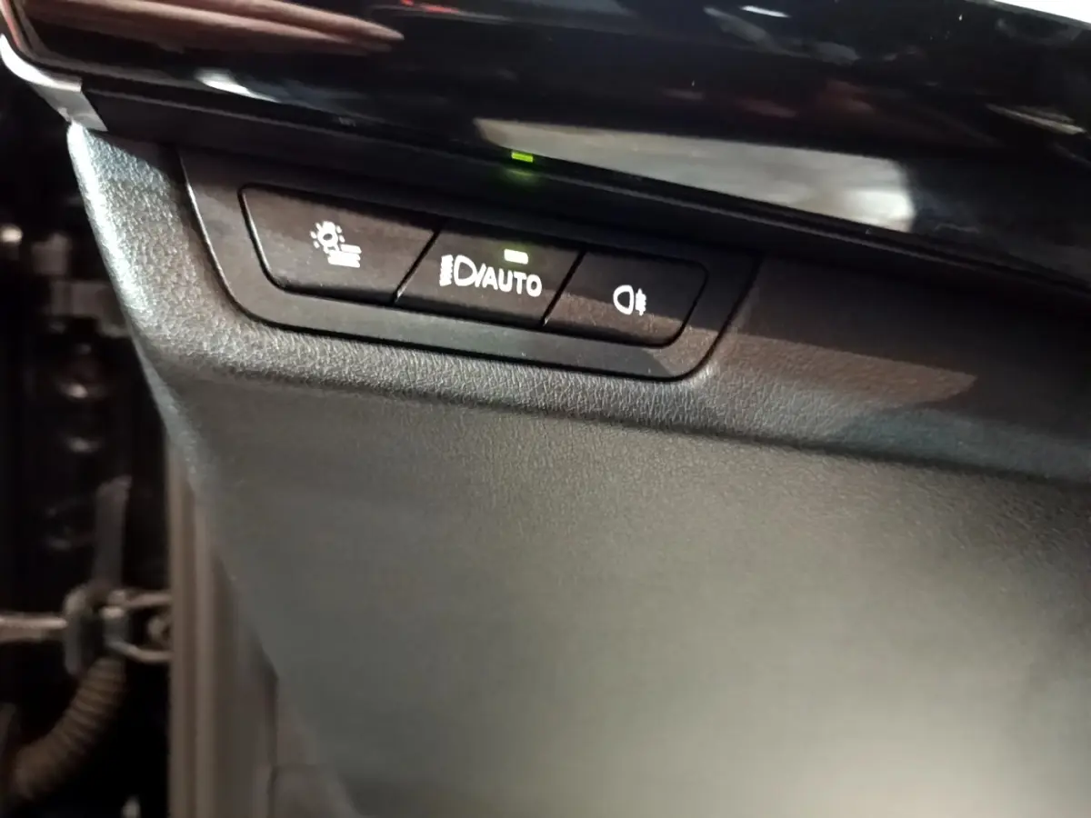 Boutons de commande des phares avec réglage automatique sur tableau de bord noir du BMW X1 xDrive23i M Sport 2023.