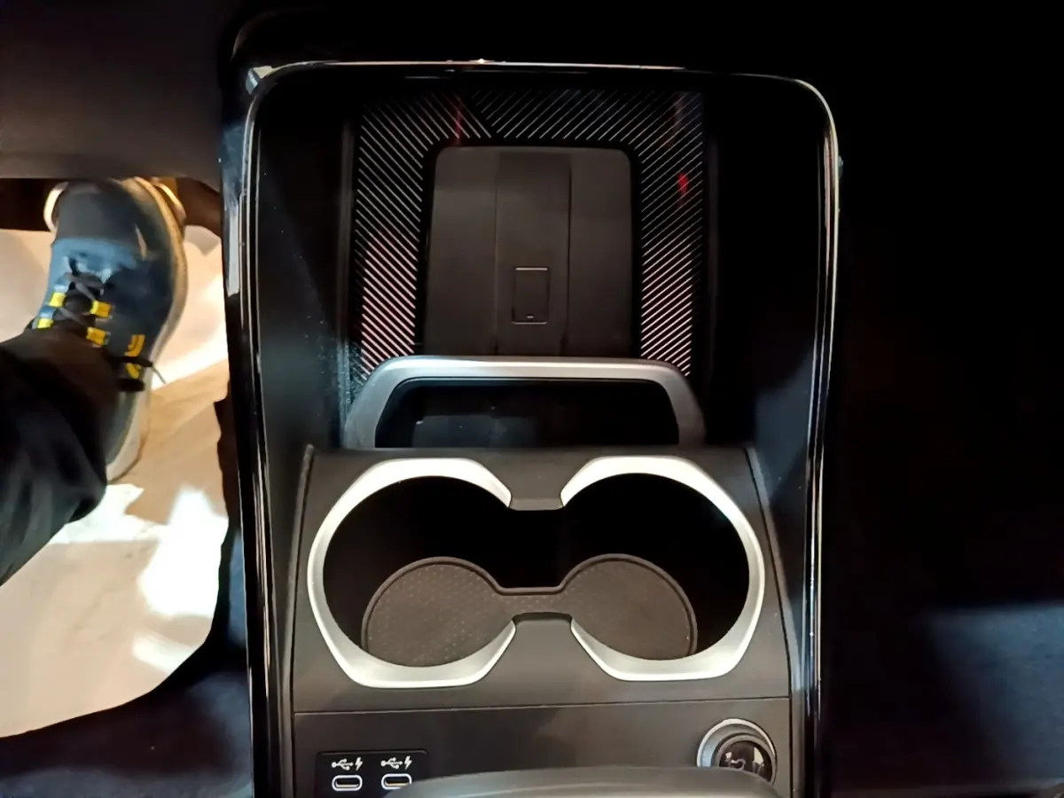 Gros plan sur la console centrale noire du BMW X1 xDrive23i M Sport 2023, avec porte-gobelets et ports USB visibles.