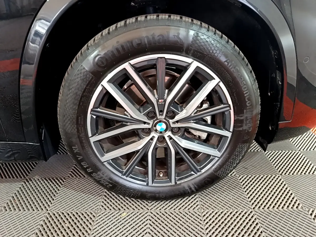 Gros plan sur la roue avant gauche noire d'un BMW X1 xDrive23i M Sport 2023 avec jante alliage distinctive.