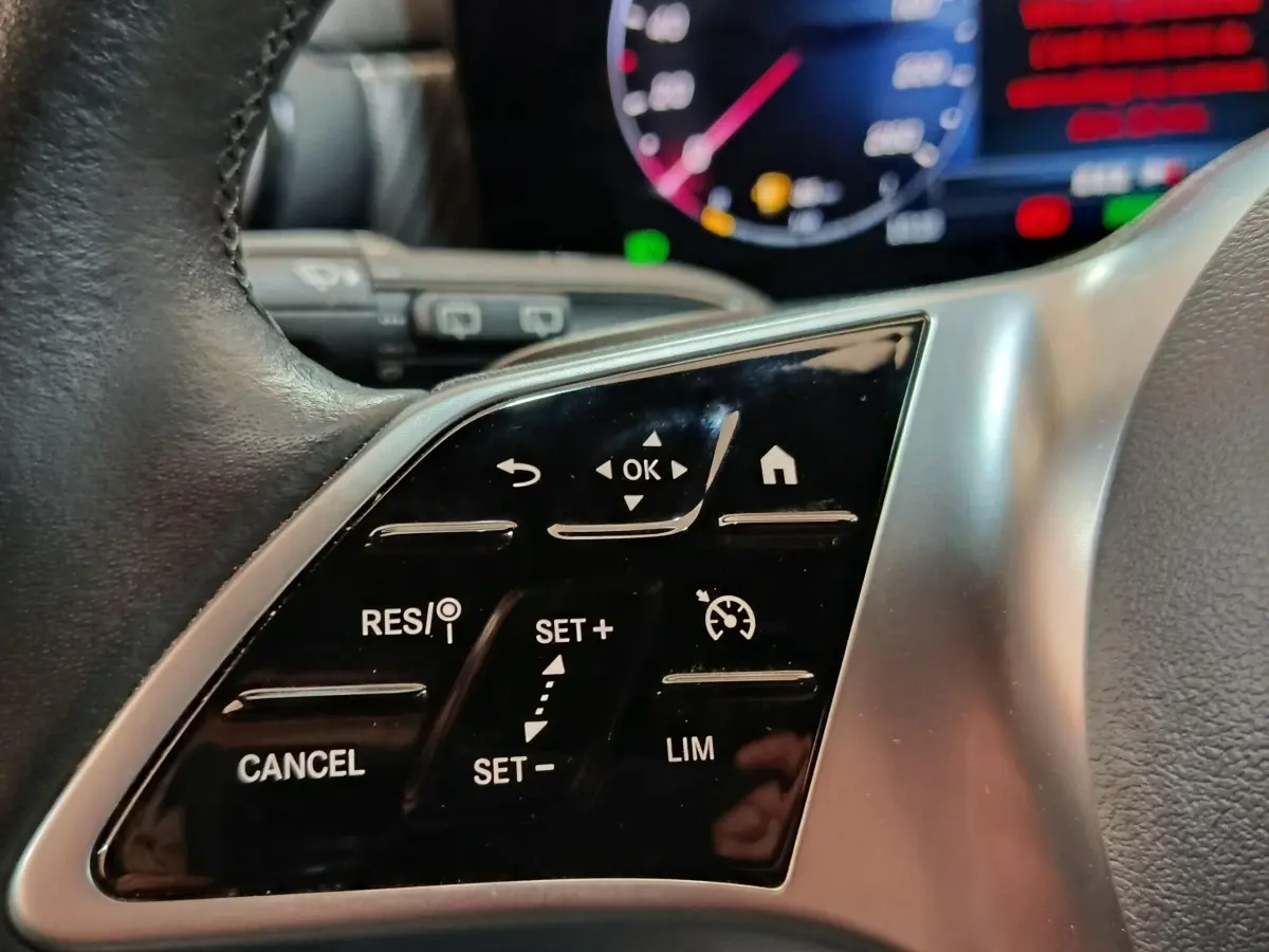 Gros plan sur le volant cuir et alu de la Mercedes Classe A 250 e Business Line 2023 avec commandes tactiles multifonctions.