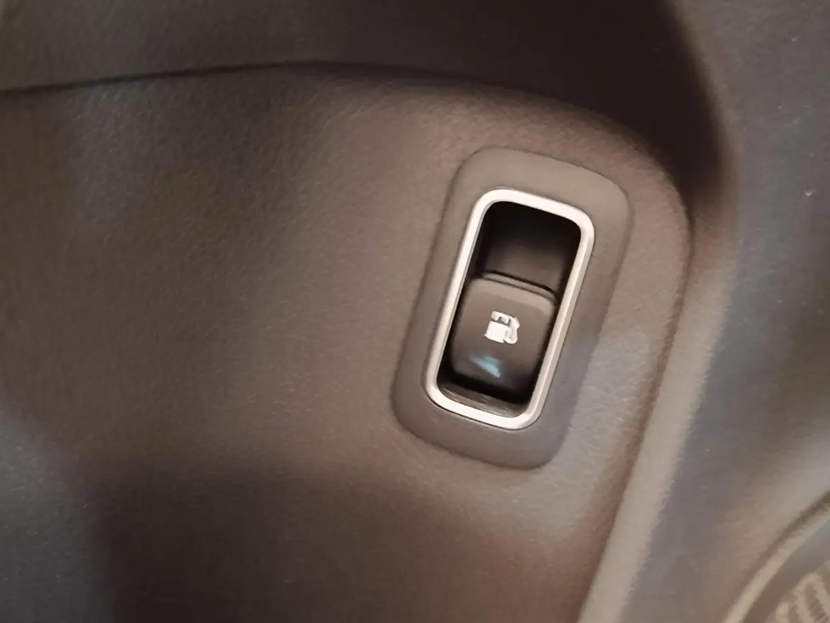 Gros plan sur le bouton d’ouverture de trappe à carburant dans l’habitacle gris foncé d’une Mercedes Classe A 250 e 2023.