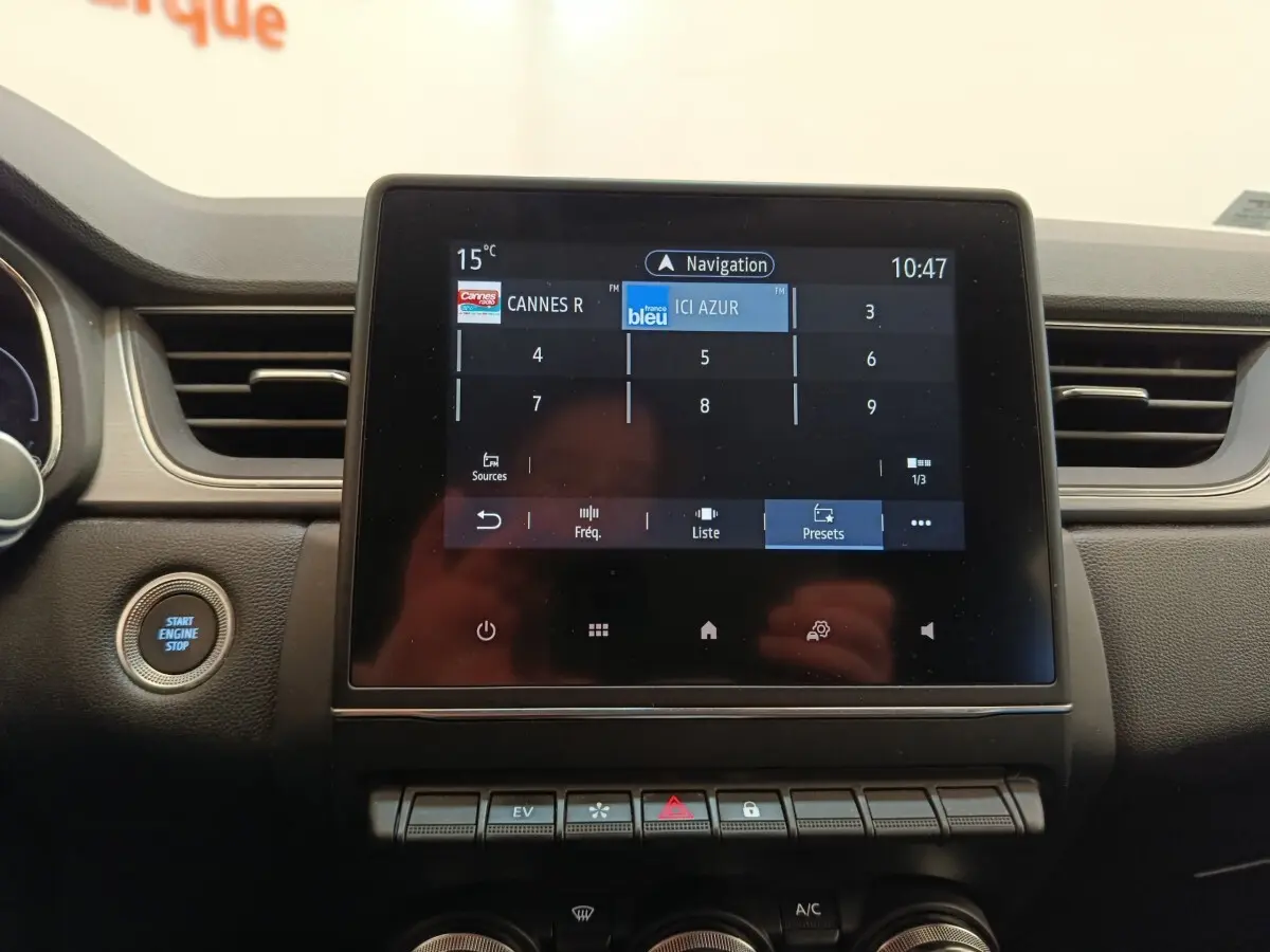 Vue rapprochée de l’écran tactile central du tableau de bord du Renault Captur Intens E-TECH gris clair, avec bouton démarrage visible.
