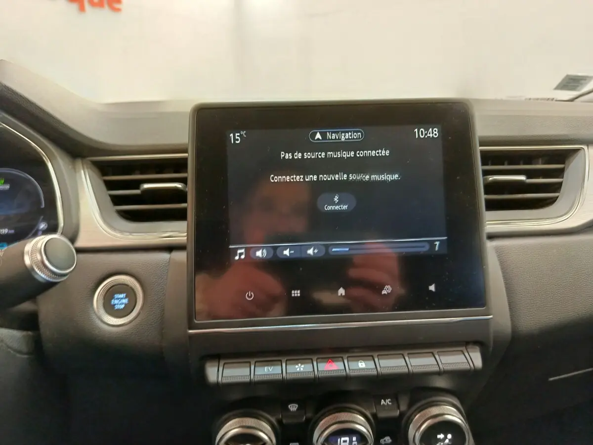 Vue rapprochée du tableau de bord du Renault Captur gris clair, écran tactile central avec commandes et bouton démarrage.