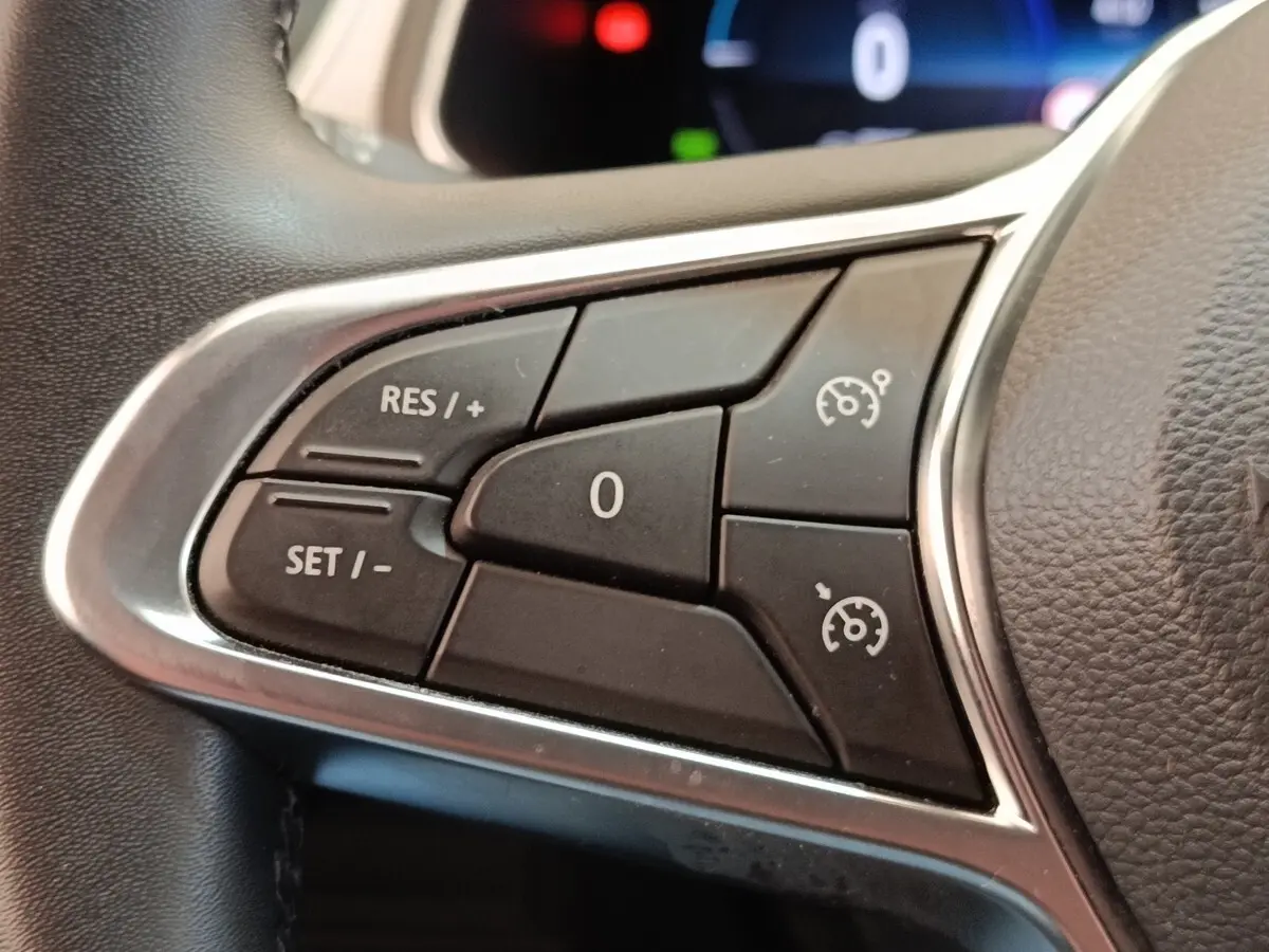 Gros plan sur les commandes du régulateur de vitesse au volant cuir du Renault Captur gris clair Intens E-TECH 2021.
