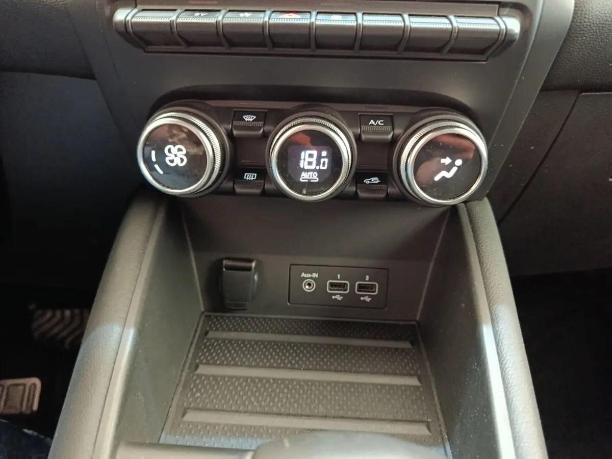 Vue rapprochée de la console centrale du Renault Captur gris clair 2021, avec commandes climatisation et ports USB visibles.