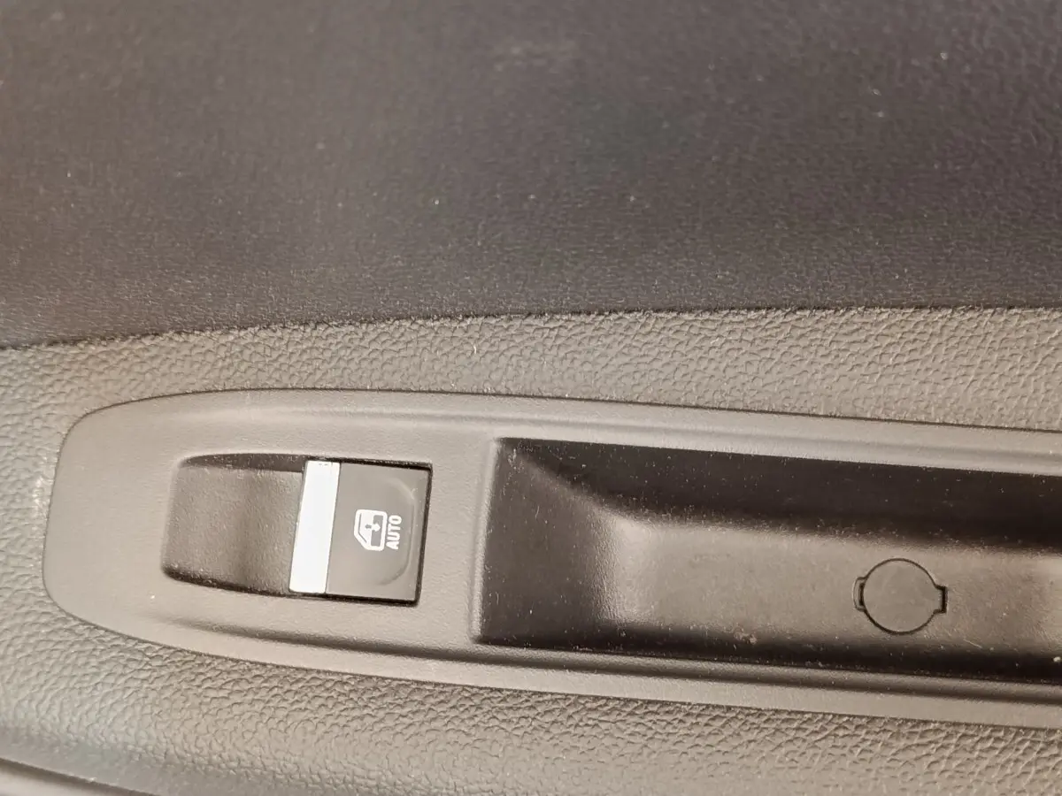 Gros plan sur le bouton de commande de lève-vitre automatique côté conducteur du Renault Captur gris clair Intens E-TECH 2021.