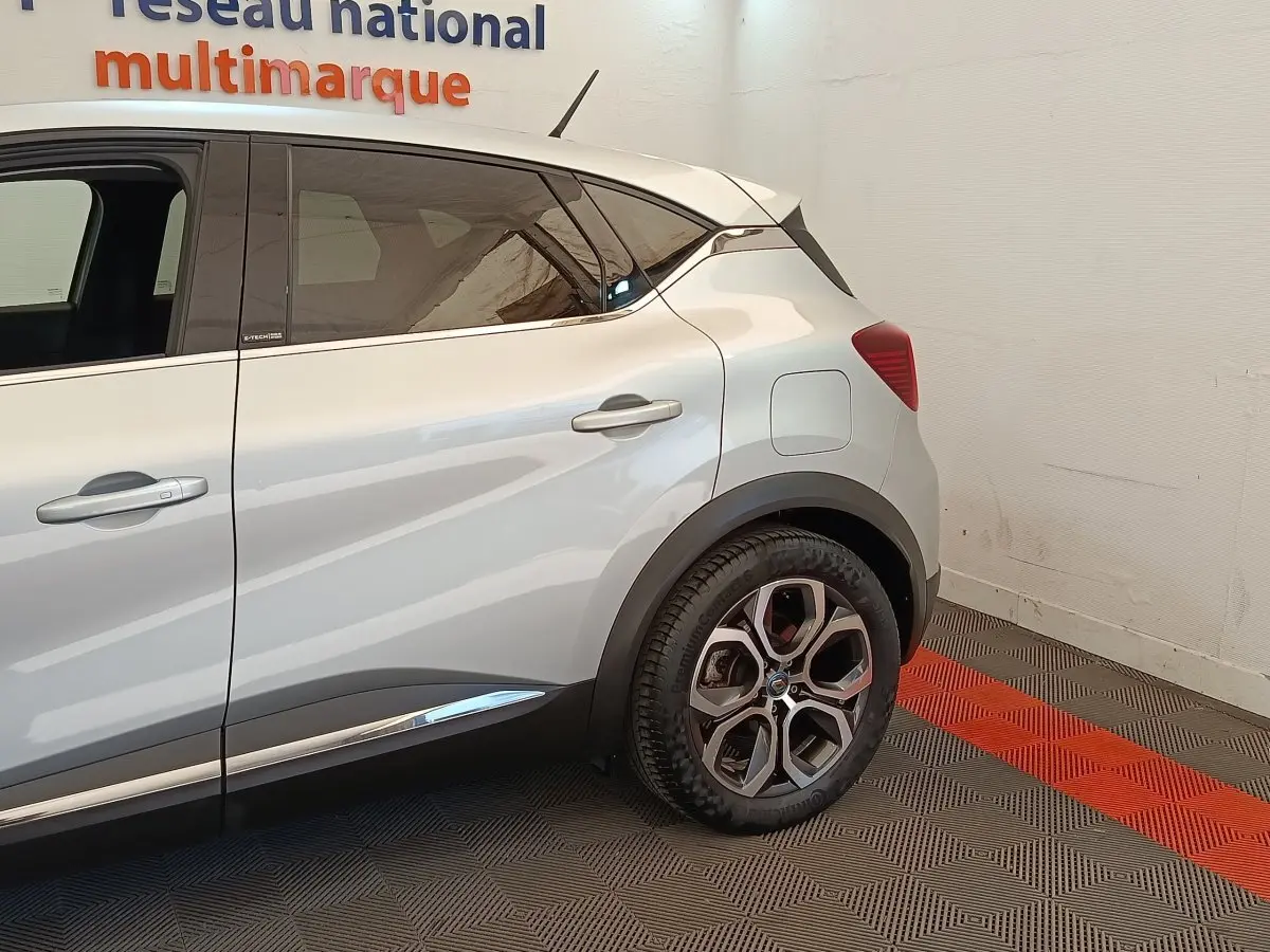 Vue côté droit arrière du Renault Captur gris clair Intens E-TECH Plug-in 160 avec détails de porte et jante visibles.