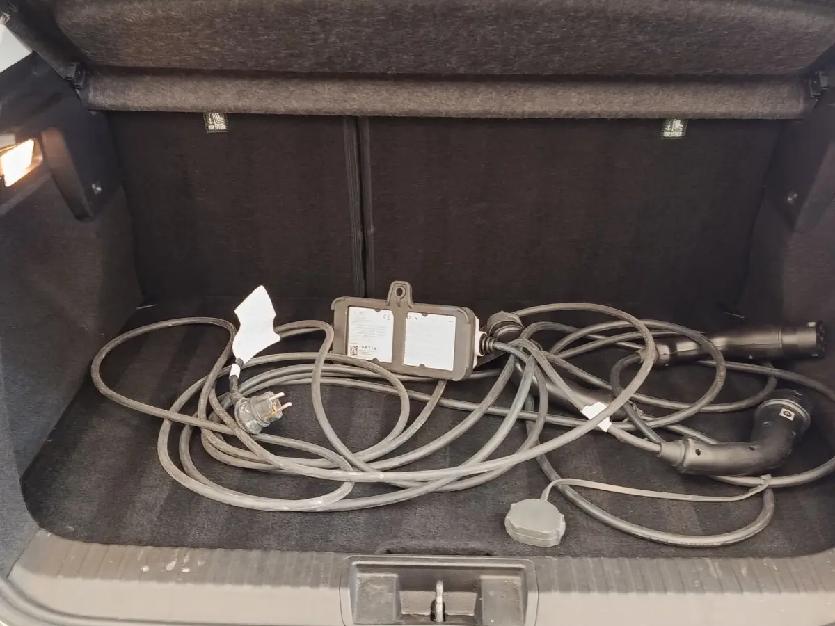 Coffre ouvert d’un Renault Captur gris clair 2021 avec câble de recharge hybride posé à plat.
