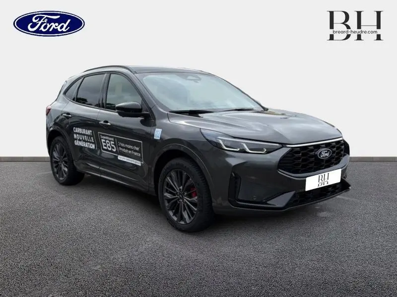 Ford Kuga gris Magnetic vu en 3/4 avant droit avec jantes noires et marquage E85 sur la porte côté gauche.