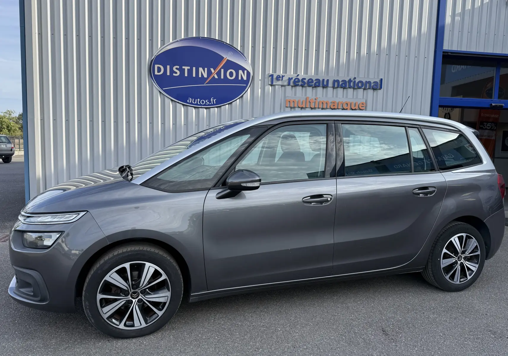 Vue de profil côté gauche d'un Citroën Grand C4 Spacetourer gris 2019 avec jantes alliage bicolores et attelage visible.