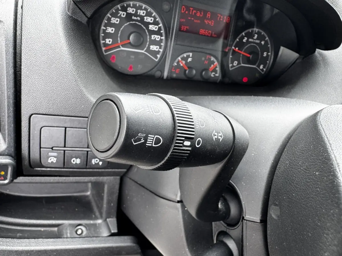 Gros plan sur la commande des phares et clignotants du tableau de bord d'un Citroën Jumper blanc, vue côté conducteur.