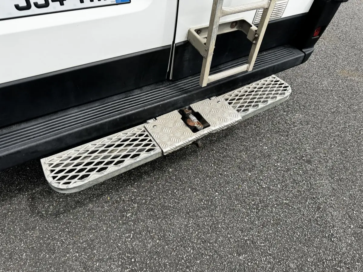 Vue rapprochée du marchepied arrière en métal sur la partie basse arrière droite du Citroën Jumper blanc.