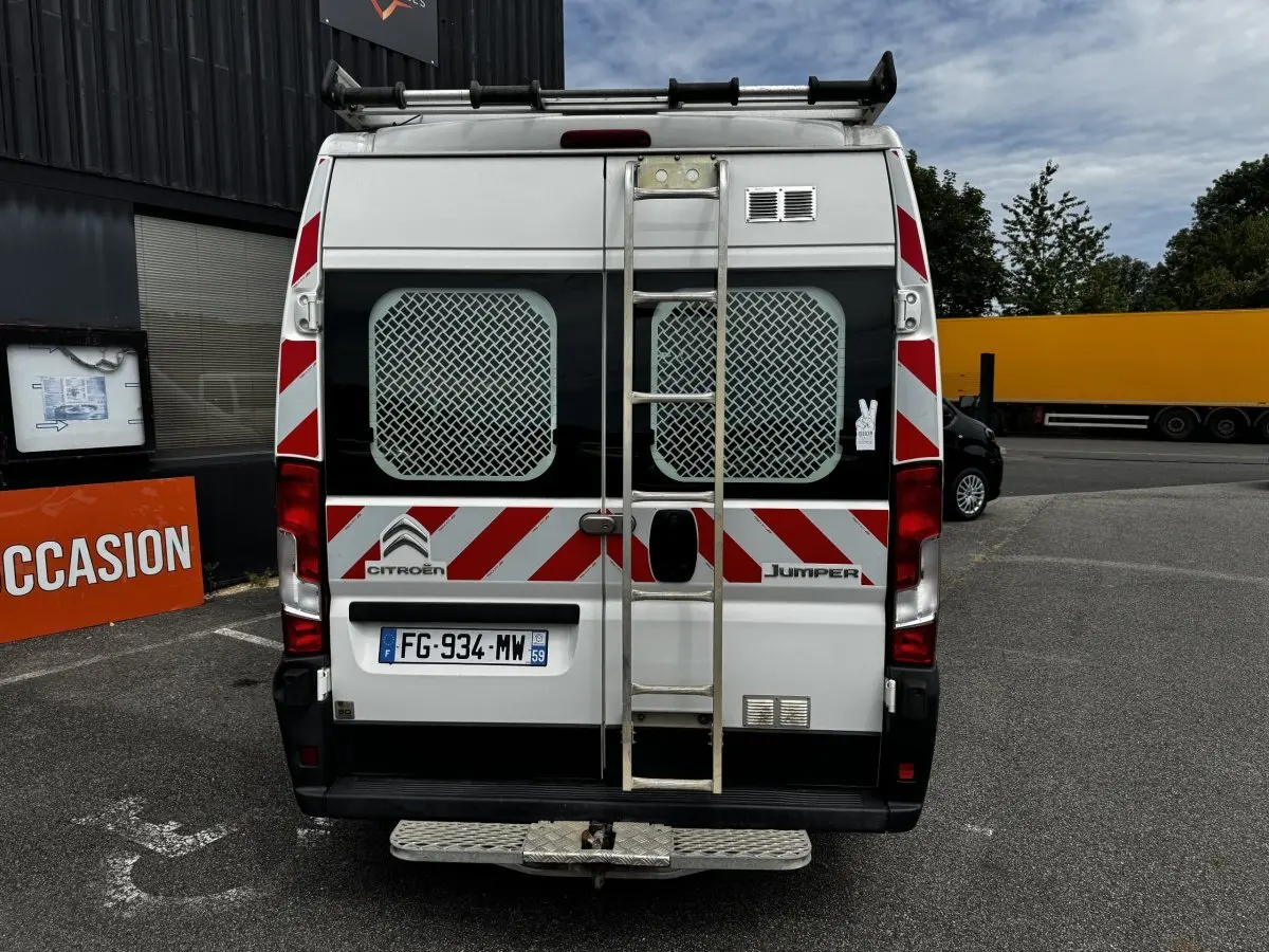 Vue arrière d’un Citroën Jumper blanc 2019 avec échelle métallique centrale et bandes rouges réfléchissantes.