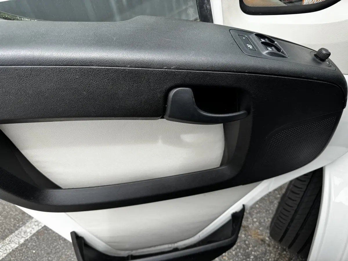 Gros plan sur la porte intérieure avant droite blanche du Citroën Jumper avec poignée et commandes de vitres noires.