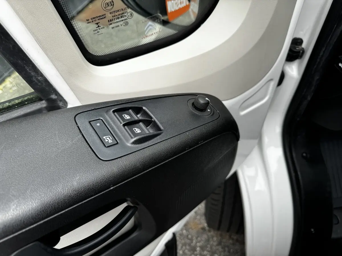 Détail des commandes de lève-vitres et réglage des rétroviseurs sur la porte avant gauche blanche d’un Citroën Jumper 2019.