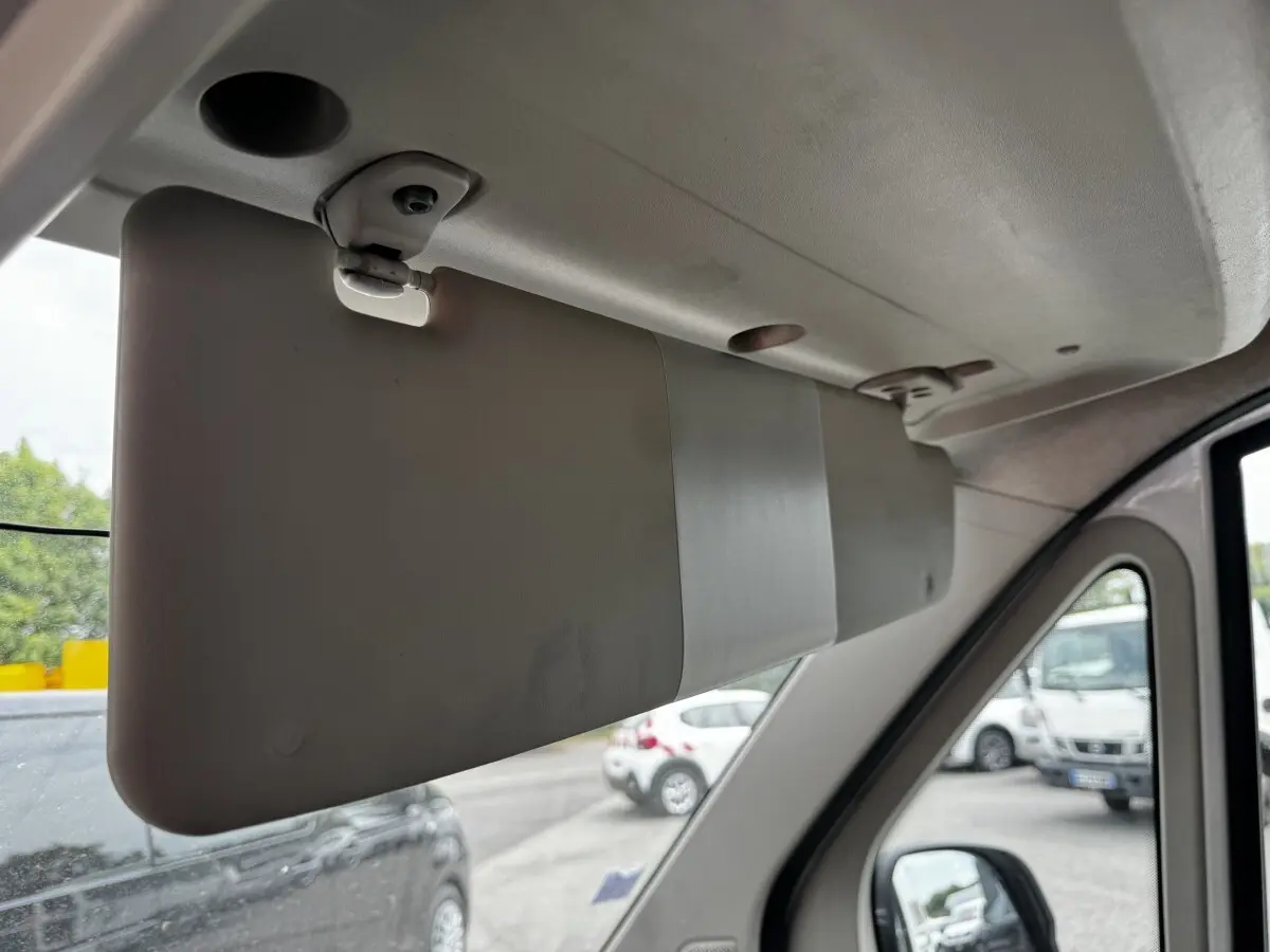 Détail intérieur du pare-soleil côté conducteur du Citroën Jumper blanc, vue vers l’avant avec rétroviseur et extérieur flou.