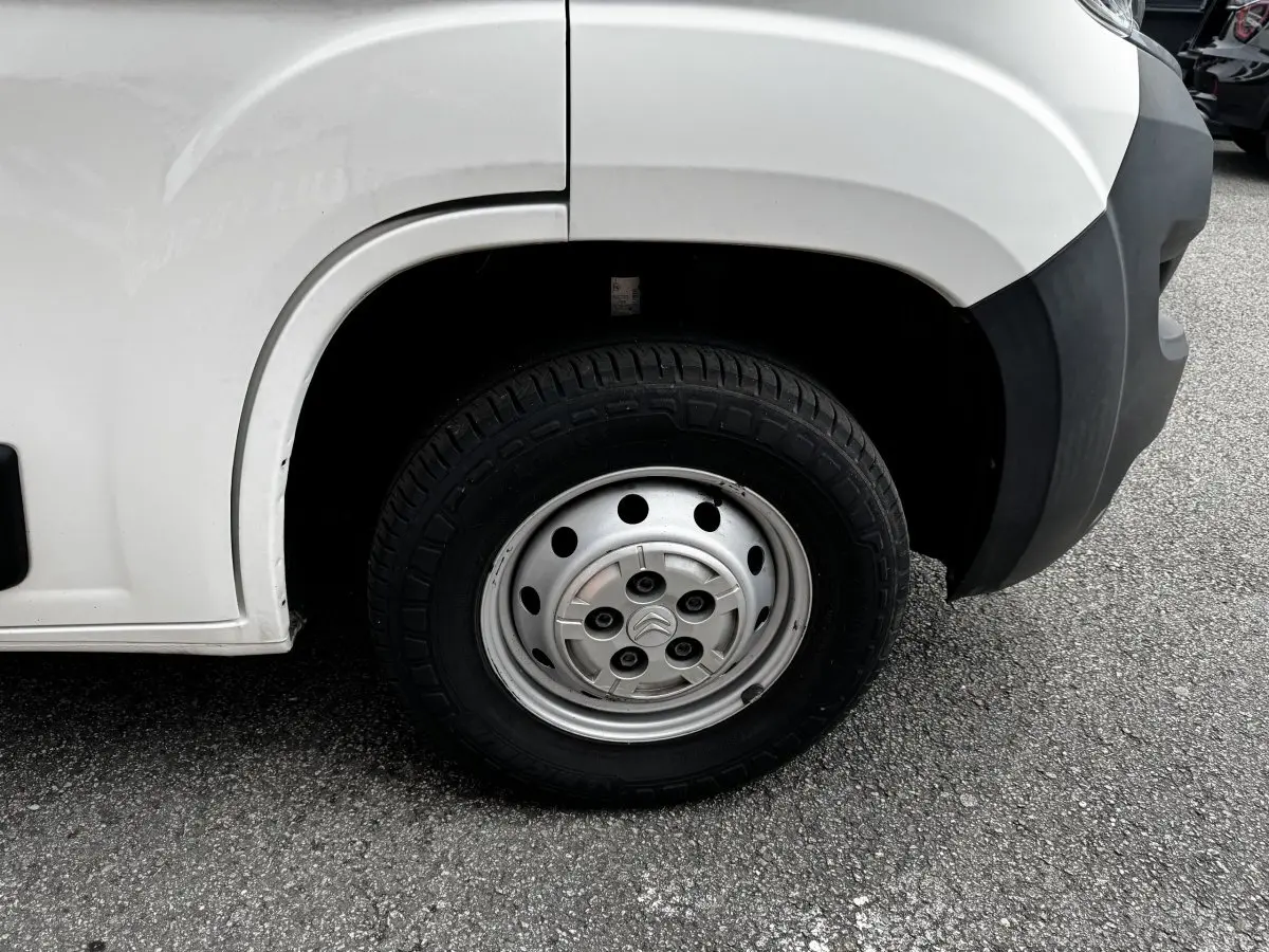 Gros plan sur la roue avant droite en jante acier argentée du Citroën Jumper blanc, avec partie de l'aile et pare-chocs noir visible.