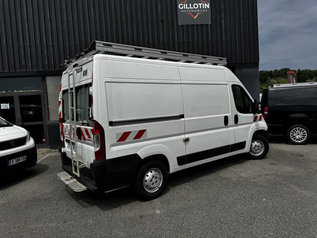 Vue 3/4 arrière droite d’un utilitaire Citroën Jumper blanc avec marquages rouges et échelle sur porte arrière.