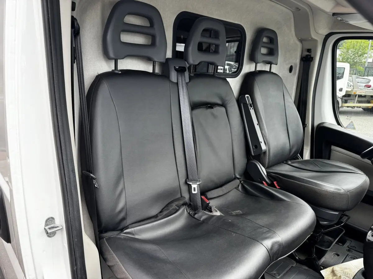 Vue intérieure côté conducteur du Citroën Jumper blanc 2019, sièges avant en cuir noir avec ceinture de sécurité centrale.