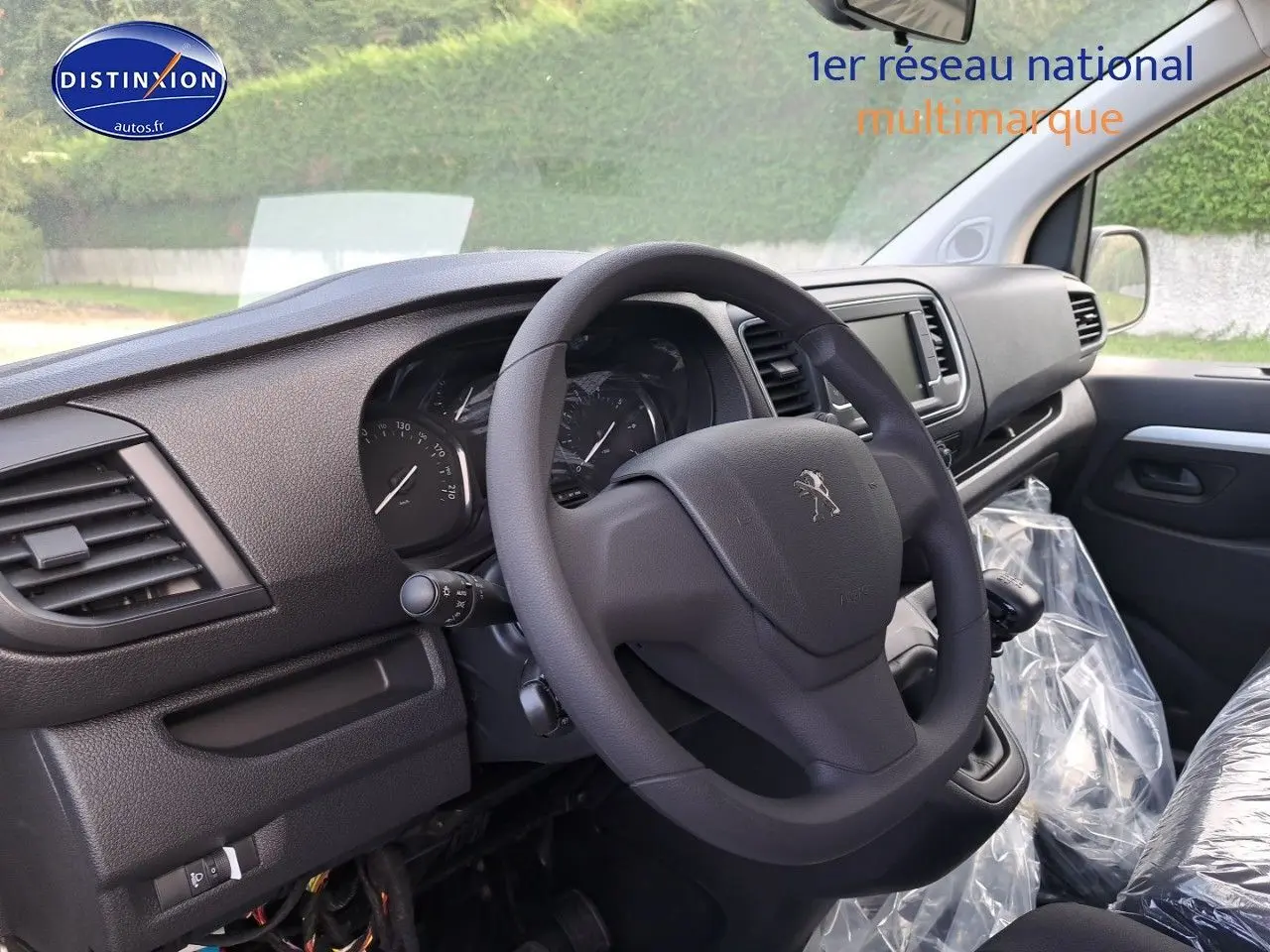 Vue intérieure côté conducteur du Peugeot Expert Blanc Kaolin 2023, volant et tableau de bord en plastique noir.