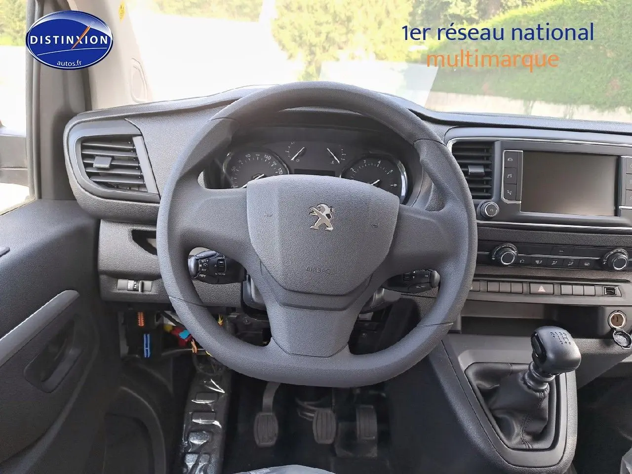 Vue intérieure du poste de conduite du Peugeot Expert Blanc Kaolin, volant et levier de vitesse manuelle visibles.