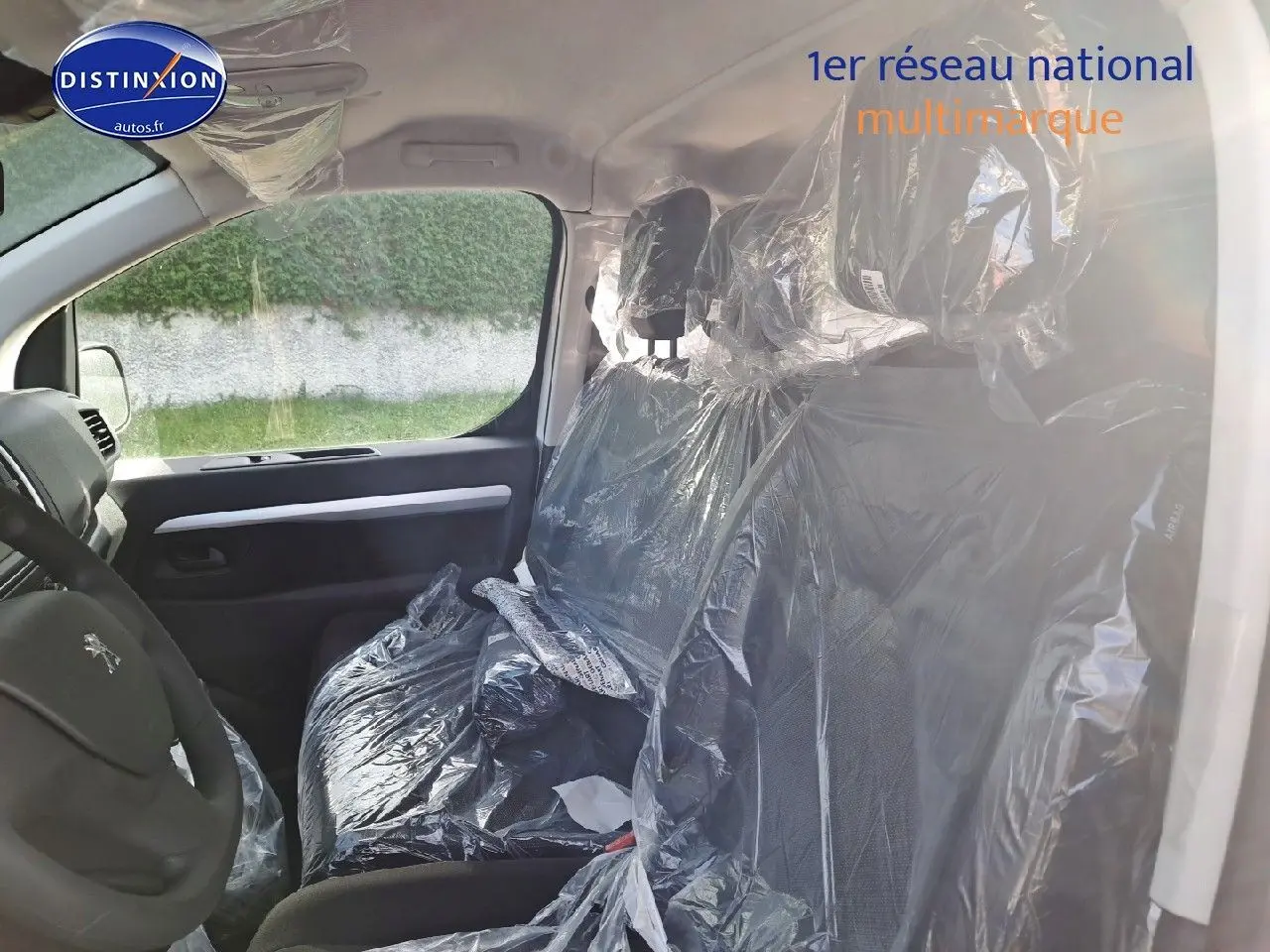 Vue intérieure côté conducteur du Peugeot Expert Blanc Kaolin 2023, sièges avant protégés par film plastique.