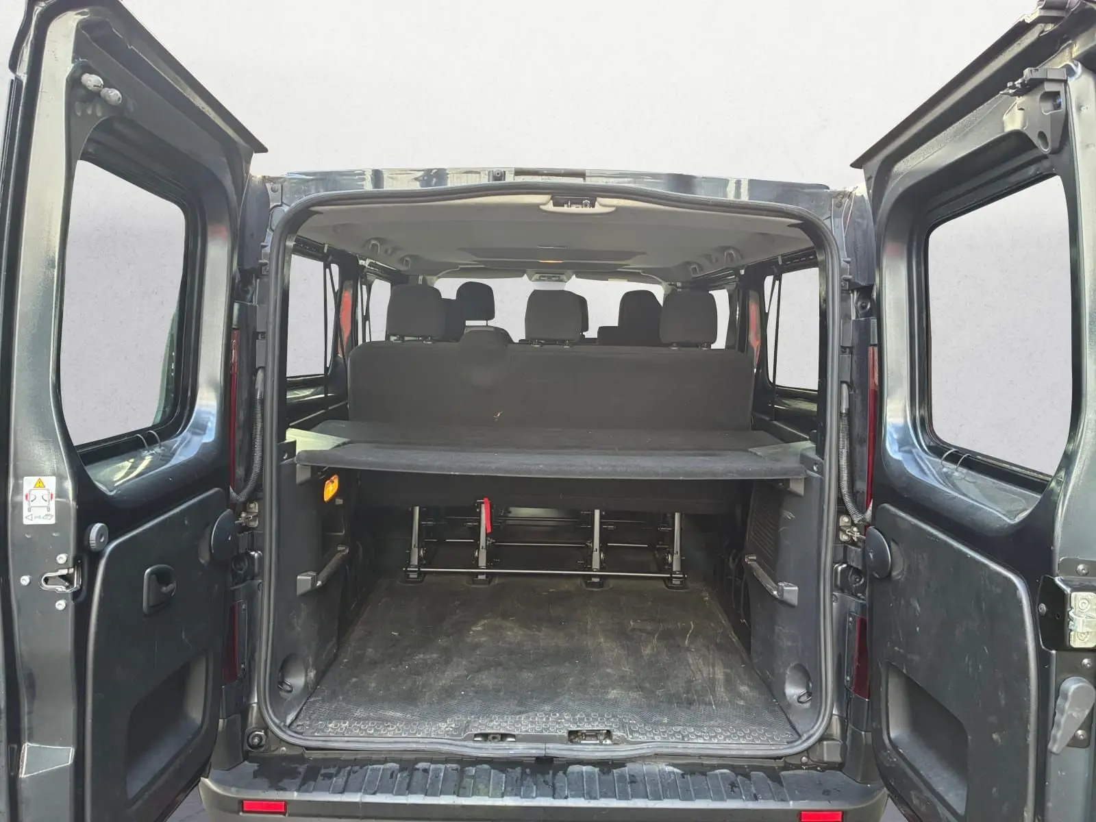 Vue arrière ouverte du Renault Trafic Combi gris foncé métal, montrant l'espace de chargement et les sièges arrière.