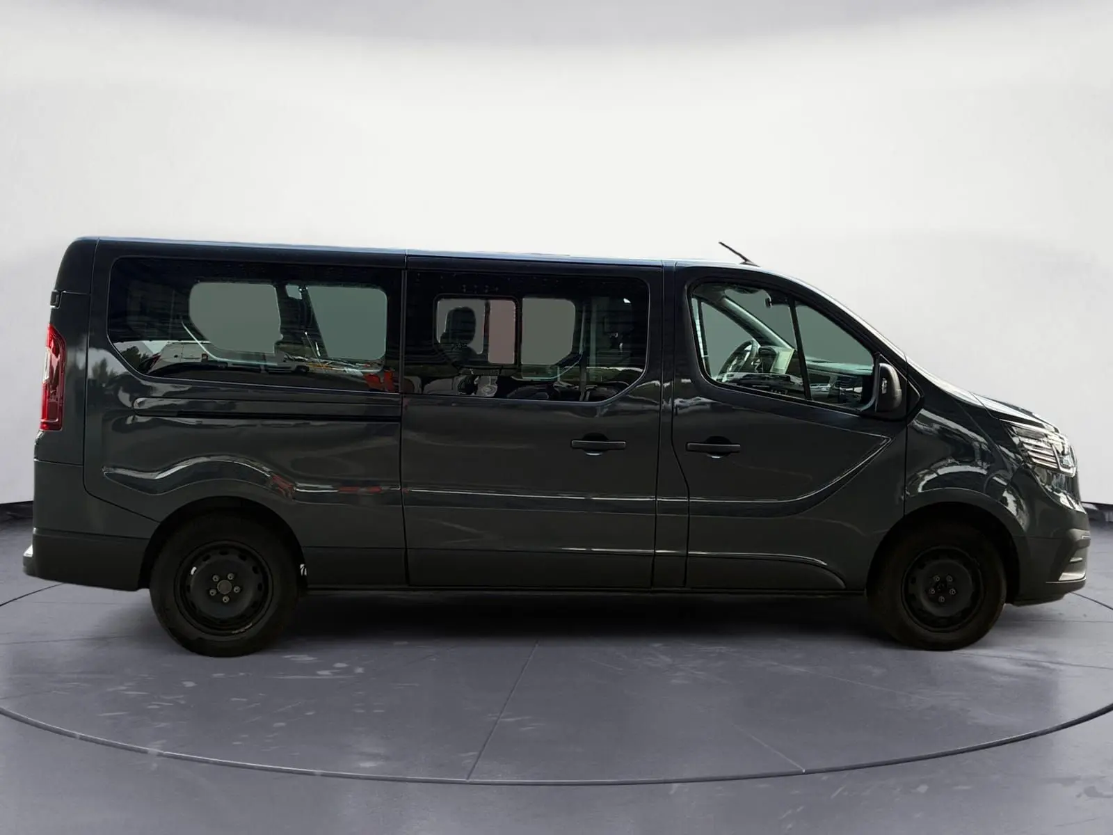 Profil latéral droit d'un Renault Trafic Combi gris foncé métallisé 2023 avec vitres teintées et roues acier noires.